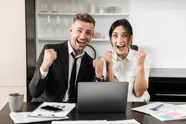 Impresionado hombre de negocios guapo emocional trabaja en interiores con su colega mujer con documentos y computadora portátil . — Foto de Stock