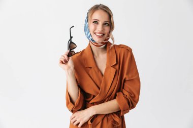 Güneş gözlüğü holding beyaz duvar arka plan üzerinde izole ipek şık eşarp poz giyen mutlu genç kadın.