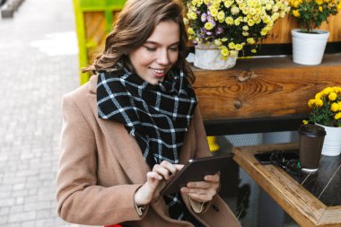 Kafe mekanlarda oturan tablet bilgisayar kullanan güzel genç kadın.