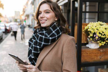 Açık havada tarafından street yürüyüş tablet bilgisayar kullanan güzel mutlu genç kadın.