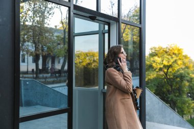 Cep telefonuyla konuşurken sokak içme kahve tarafından açık havada yürüyen kadın.
