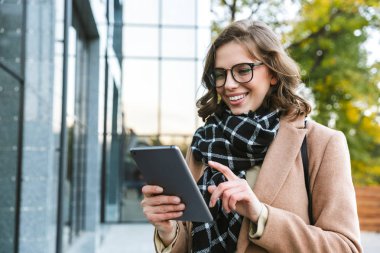 Tablet bilgisayar kullanarak street tarafından açık havada yürüyüş güzel genç kadın.