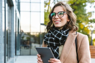 Tablet bilgisayar kullanarak street tarafından açık havada yürüyüş güzel genç kadın.