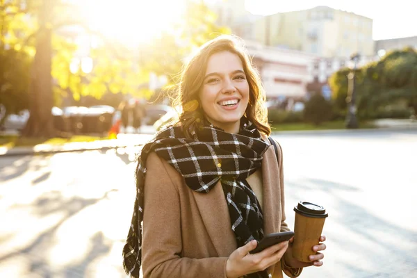 Mujer joven feliz usando el teléfono móvil al aire libre caminando por la calle . — Foto de Stock