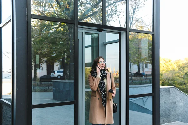 Mulher ao ar livre andando pela rua bebendo café falando por telefone celular . — Fotografia de Stock