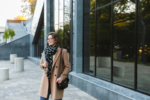 Mulher ao ar livre andando pela rua segurando computador portátil . — Fotografia de Stock