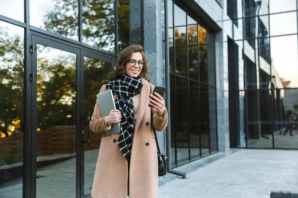 Kadın açık havada tarafından dizüstü bilgisayar istimal hareket eden telefon tutarak street yürüyüş. — Stok fotoğraf