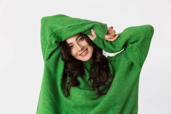 Hermosa joven vestida con suéter verde posando aislada sobre fondo blanco de la pared . — Foto de Stock