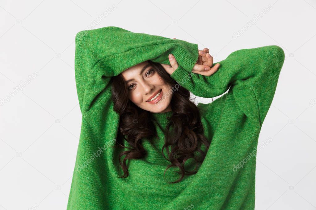 Beautiful young woman dressed in green sweater posing isolated over white wall background.