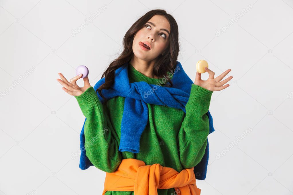 Portrait of pretty woman 30s in colorful clothes holding macaron