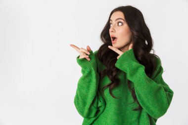 Yeşil kazak arka plan beyaz duvar işaret içinde izole poz içinde şok genç kadın giyinmiş.