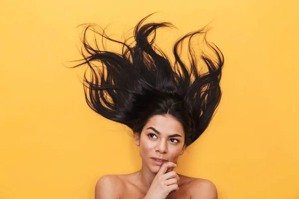 Hermosa mujer joven pensamiento yace aislado sobre fondo amarillo. Concepto de cabello saludable . —  Fotos de Stock