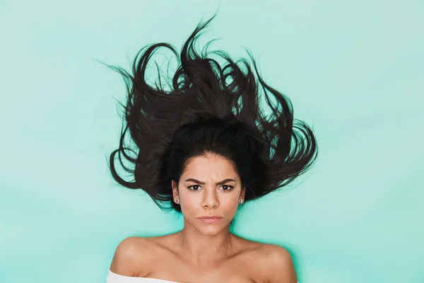 Mujer joven disgustada yace aislada sobre fondo azul claro. Concepto de cabello saludable . —  Fotos de Stock