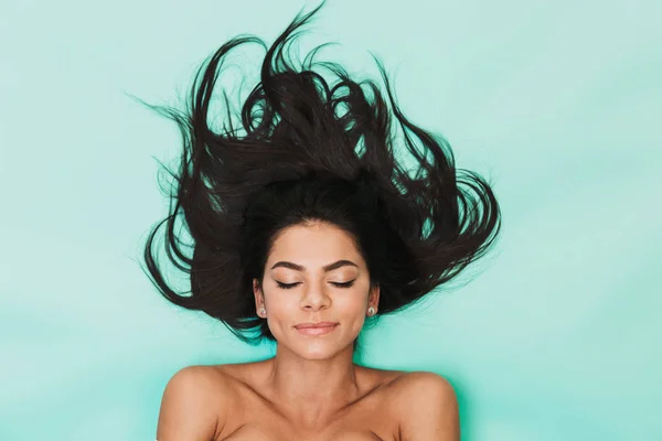 Красивая молодая женщина лежит изолированно на голубом фоне света. Здоровая концепция волос . — стоковое фото