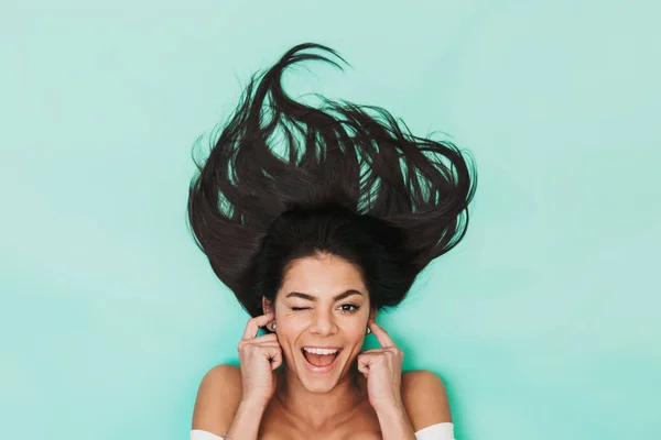 Jovem feliz encontra-se isolado em azul luz fundo cobrindo orelhas . — Fotografia de Stock