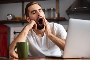 Dizüstü bilgisayar kullanan sıkılmış genç adam