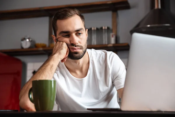 Jovem entediado usando computador portátil — Fotografia de Stock