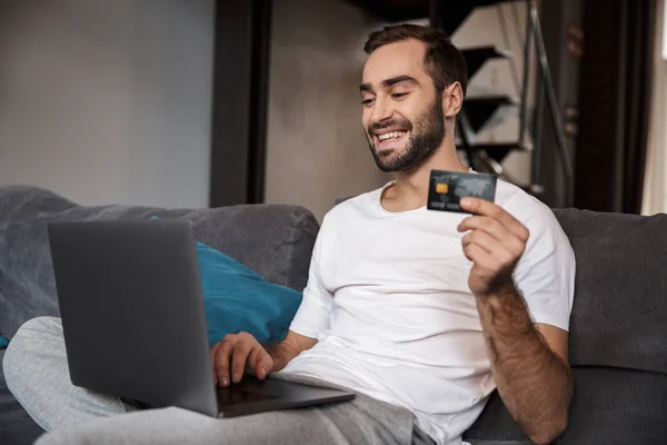 Glücklicher junger Mann sitzt auf einer Couch — Stockfoto