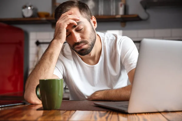 Jovem entediado usando computador portátil — Fotografia de Stock