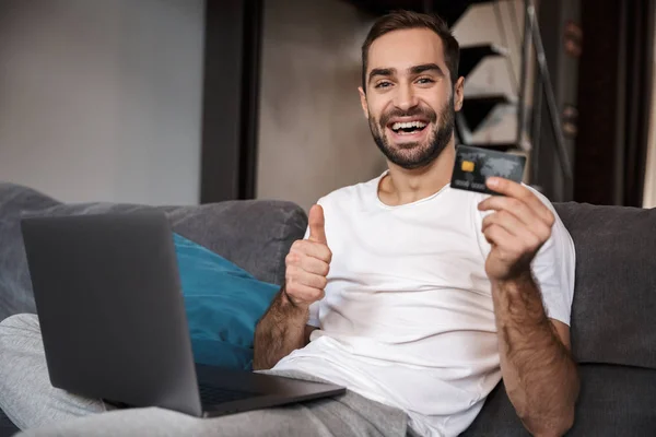 Joyeux jeune homme assis sur un canapé — Photo