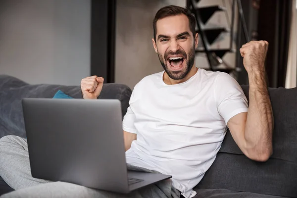 Joyeux jeune homme assis sur un canapé — Photo