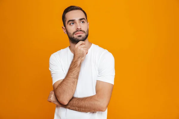 Immagine di un uomo serio 30s in t-shirt toccare il mento mentre stan — Foto Stock