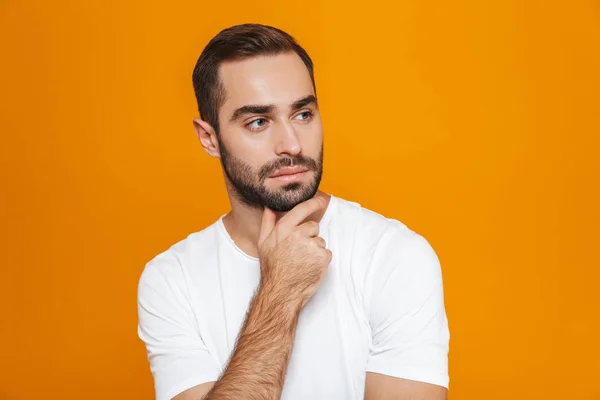 Bilden av attraktiva mannen 30s i t-shirt röra hakan samtidigt s — Stockfoto