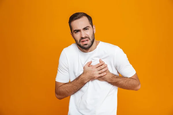Imagem do homem doente 30 anos em t-shirt tocando seu coração por causa de p — Fotografia de Stock