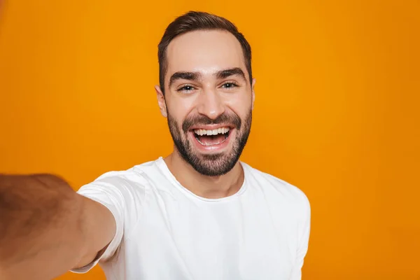 Retrato de homem amigável 30 anos em t-shirt sorrindo ao tomar sel — Fotografia de Stock