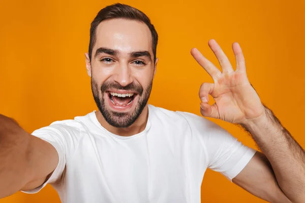 Портрет небритого мужчины 30 лет в футболке, улыбающегося во время приема сэла — стоковое фото