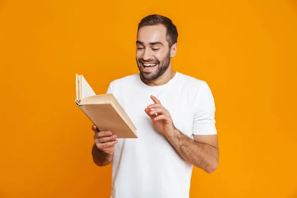 Immagine di attraente uomo anni 30 in bianco t-shirt in possesso e lettura — Foto Stock