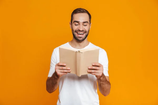 Bilden av brunett man 30s i vit t-shirt holding och läsa b — Stockfoto