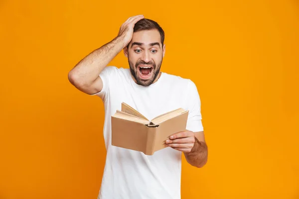 Afbeelding van opgewonden man 30s in wit t-shirt houden en het lezen van bo — Stockfoto