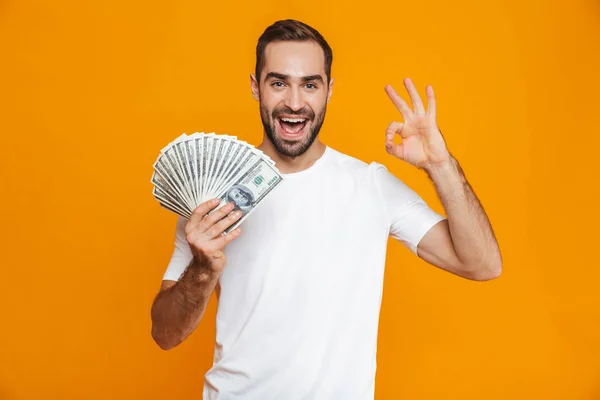 Pohledný muž 30s v oblečení drží balík peněz, — Stock fotografie