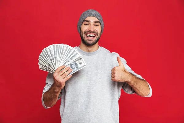 Imagen del hombre europeo de 30 años con sombrero sosteniendo ventilador de dinero, aislar —  Fotos de Stock