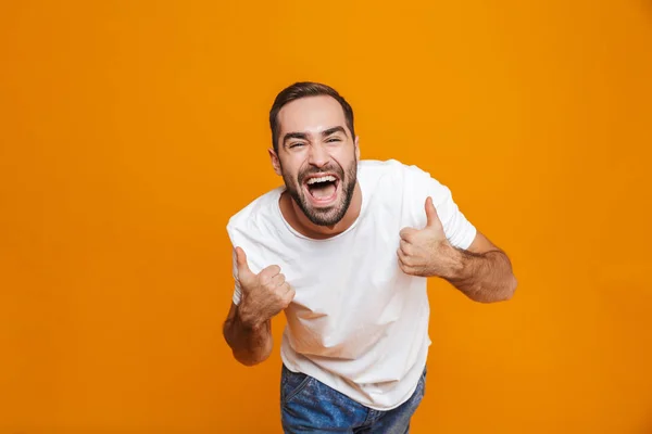 Bild eines fröhlichen Typen um die 30 im T-Shirt jubelt und Daumen zeigt — Stockfoto