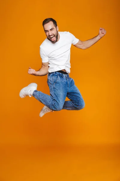 Foto de cuerpo entero del chico sin afeitar en camiseta y jeans saltando un — Foto de Stock