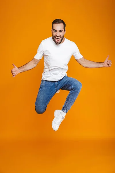 T シャツとジーンズをジャンプで陽気な男の全身写真、 — ストック写真