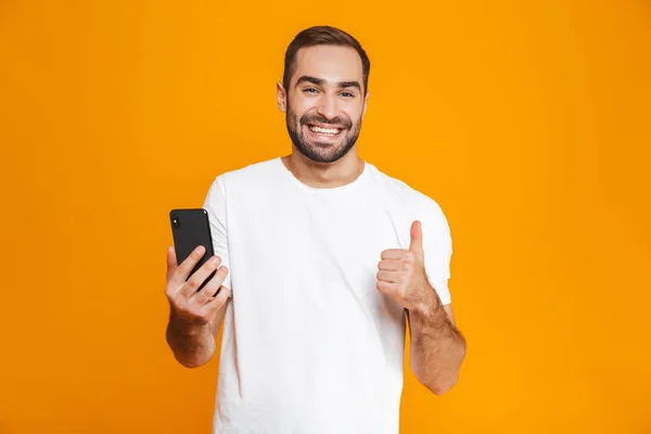 Foto van positieve man 30s in vrijetijdskleding glimlachend en houden van sma — Stockfoto
