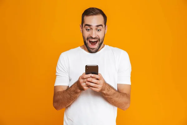 Foto van vrolijke man 30s in vrijetijdskleding glimlachend en houden van sma — Stockfoto