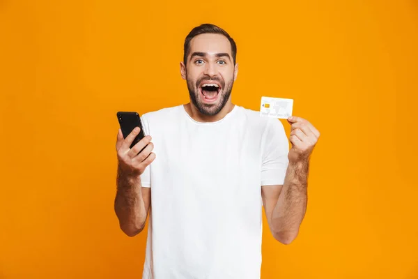 Foto av lycklig man 30s i fritidskläder som håller smartphone och cre — Stockfoto
