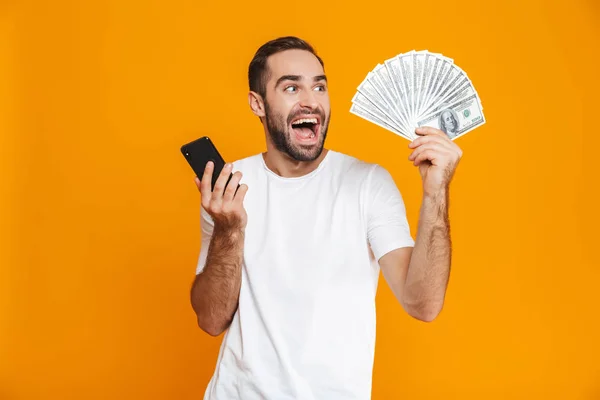 Φωτογραφία από ένα μουστάκι άνθρωπος 30s casual ντύσιμο κρατώντας το κινητό τηλέφωνο και — Φωτογραφία Αρχείου