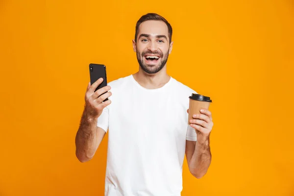 Zdjęcie z brunetka człowiek 30s w odzież codzienna, trzymając telefon komórkowy i — Zdjęcie stockowe