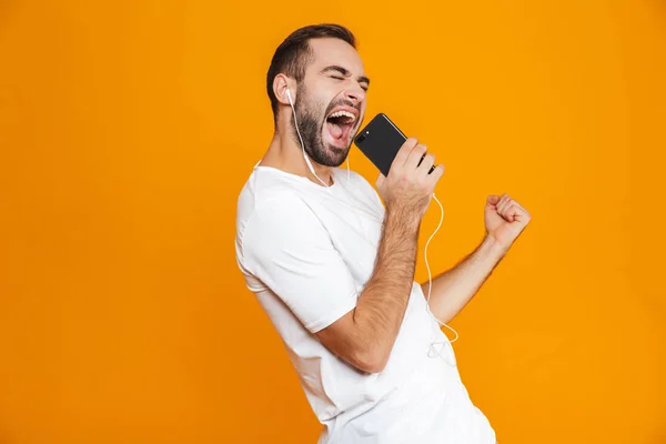Foto van de knappe man 30s zingen tijdens het gebruik van de koptelefoon en mobi — Stockfoto