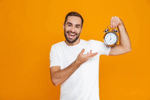 Foto av attraktiv man 30s i fritidskläder holding väckarklocka, — Stockfoto