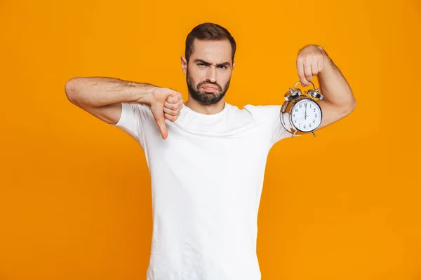 Foto de hombre molesto de 30 años en ropa casual con reloj despertador, isola —  Fotos de Stock