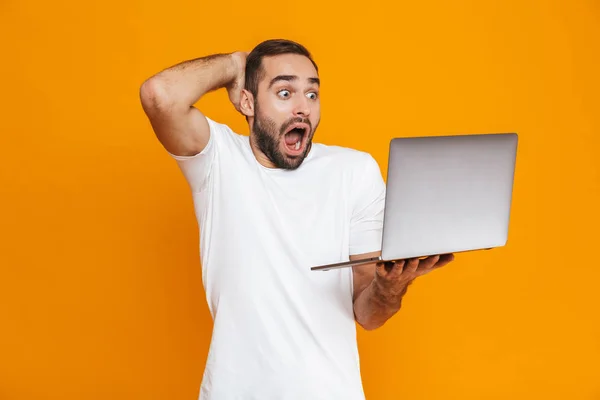 Retrato de homem surpreso 30 anos em branco t-shirt segurando prata la — Fotografia de Stock