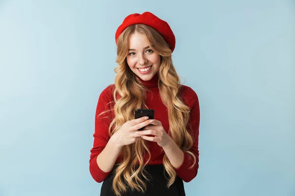 Beyaz kız 20'li yaşlarda giyen kırmızı bere smartphone kullanarak fotoğrafı — Stok fotoğraf