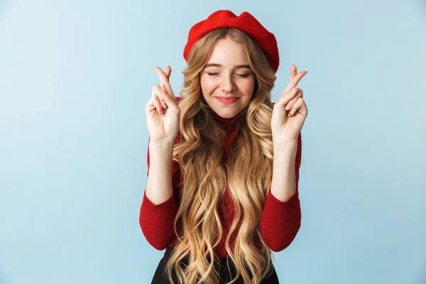 Imagen de una linda mujer rubia de 20 años con boina roja manteniendo los dedos — Foto de Stock