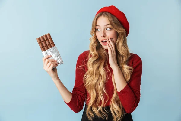 Imagem de menina atraente 20s vestindo boina vermelha comendo chocolate — Fotografia de Stock